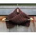 Display of the Grid Crochet Scarf on a hanger in front of a wooden fence.