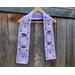 Display of the Mom Crochet Scarf on a hanger in front of a wooden fence.