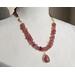 Necklace with pink quartz pendant with pink quartz nuggets, cream colored shell beads, and tiny red garnet beads with gold hook clasp