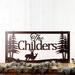 Rectangular metal family name plaque with buck and doe deer, in copper vein powder coat.