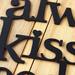 Close up of lettering on our Always Kiss Me Goodnight metal wall decor, in matte black powder coat.
