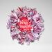 Handmade rustic Christmas wreath with red and white ribbons, snowflake accents, and farmhouse holiday decor on a white background.