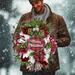 Man holding Merry Christmas wreath with plaid ornament, red berries, and white ribbons against a snowy winter backdrop.