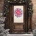 Red and white rustic winter wreath with snowflake accents and candy cane stripes, hanging on a brown farmhouse front door.