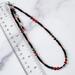 Black and red beaded choker necklace next to a ruler.
