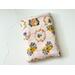 this beehive book sleeve has a light pink background with beehives and bees all over the bee book cover. The bee book holder has a pocket