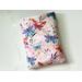 the butterfly book sleeve has a light pink background with white flowers and watercolor butterflies