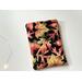 this fall kindle sleeve has a black background with fall leaves all over the autumn kindle cover