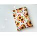 this sunflower book sleeve has a white background with different sizes of flowers with green and red leaves