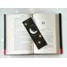 this starry page holder has a moon in the middle with a cat sitting on the moon with a set of hands at the bottom of the bookmark with stars around the moon and a star in the center and top of the bookmark