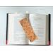 the laminated bookmark is in the middle of an open book with fairy lights around the book on a white table