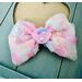 Textured floral inspired soft pink, peach, blue, & yellow, hair bow, with pink sparkle shell charm on top. Bow is sold individually. 