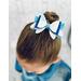 My 4 year old modeling a blue and white glitter 4 layer bow. Top left corner of bow has dripping iridescent blue rhinestones.