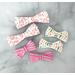 2" & 3 " size bows on 3/8" ribbon. 4 loops on each side. Top is rainbow print, to right is a colorful dash print, bottom is a stripe print. 