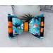Close up of teal & black Halloween print hair bow with loops of orange ribbon. 4 layers total. Bow is sold individually. 