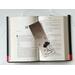 the book mark is in the middle of an open book with fairy lights above the book on a white table