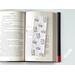 the laminated bookmark is on top of an open book on a white table