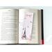 the pink page holder is on top of an open book on a white table