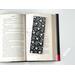 the laminated bookmark is on top of an open book