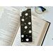 this flower bookmark is on top of an open book on a white table