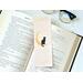this cat page saver is on top of an open book with a pair of glasses on a white table