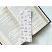 This bookish owl bookmark has a light brown background with little stars in the background. The page saver has book stacks, glasses and owls covering the bookish book mark