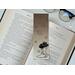 the laminated bookmark is on top of an open book with a pair of glasses on a white table
