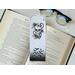 this scary book mark is on top of an open book with a pair of glasses  on a white table