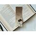 this western bookmark has ombre brown background with cowboy boots with a hat on top of the boots. there are flowers all over the book mark