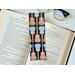 this instrument bookmark is in a real life setting with an open book and a pair of glasses