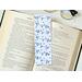 this cute bookmark has a white background with outline blue tree branches with blue flowers on them. With small blue flower all over the page holder