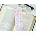 This bow bookmark has a light pink background with gold Eiffel Towers all over, different thickness of bows, pink flowers, and white sparkles all over the bookmark