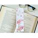 This pink floral bookmark has a gold Eiffel Tower in the bottom left corner with pink watercolor flowers blowing around the Tower. There are pink flowers, butterflies, and an airplane all over the top page holder