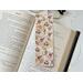 this rustic bookmark is on top of an open book with a pair of glasses peeking from the top with fairy lights on the right side of the book