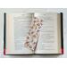the laminated bookmark is in the middle of an open book with fairy lights around the book on a white table