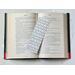 the elegant bookmark is in the middle of an open book with fairy lights around the book on a white table
