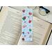 this hot chocolate bookmark has a blue background with hot cocoa, candy cane, and snowflakes all over the page saver
