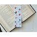 this hot chocolate bookmark is on top of an open book on a white table