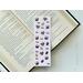 this coffee bookmark has a light purple background with medium coffee beans small and some making a heart shape. there are purple coffee cups all over the coffee bean page saver
