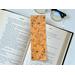 the flower bookmark is on top of an open book with a pair of glasses on a white table above the book
