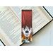 this skull bookmark has a ombre red background with lightning coming the sky and there is a crack on the right side. on the bottom there is a skull with wings coming out from a smoking flame