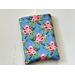 this floral book sleeve has a blue background with pink roses and green leaves all over the book holder