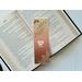 this owl bookmark has an ombre brown background with an owl reading a book in the middle & leaves in the bottom right and top left corner