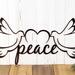 Close up of peace script lettering on our peace doves metal sign, in copper vein powder coat.