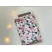 an ereader is peeking out of the floral kindle cover on a white table an with fairy lights on the left side