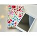 the ebook is sitting on top of the floral kindle cover on a white table with fairy lights on the left side.