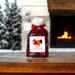 Handmade apple cinnamon potpourri displayed on a wooden table, with a fireplace and a snow-covered pine tree blurred in the background.