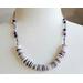 necklace with 1/2" in diameter white and purple shell button style beads, smaller faceted charoite gemstones, and a stainless steel chain 