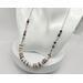 necklace with 1/2" in diameter white and purple shell button style beads, smaller faceted charoite gemstones, and a stainless steel chain 