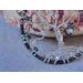 tree trunk is braided with wire and adorned with gray metal owl charm